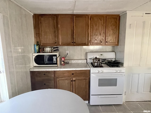 665 W Wilmot St, Chillicothe, IL 61523 - kitchen with gas range gas stove, tile patterned floors, light countertops, and brown cabinetry