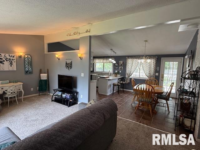 603 Sherry St, Colchester, IL 62326 - living room featuring a chandelier, dark tile patterned flooring, a textured ceiling, and dark colored carpet