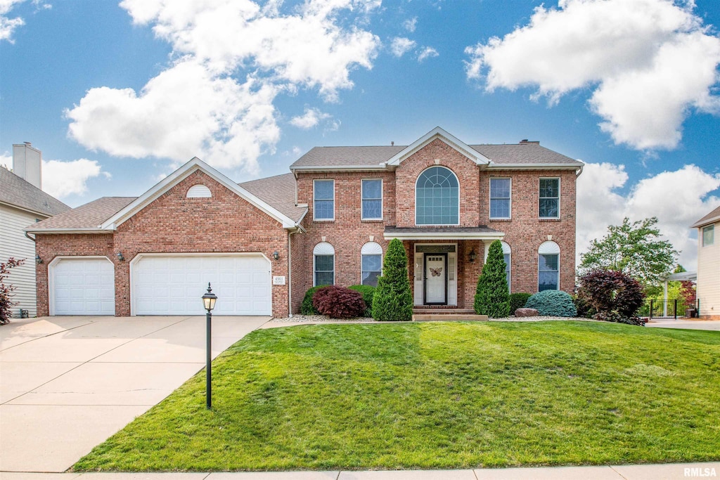 4901 N Weaverridge Blvd, Peoria, IL 61615 - view of front of house featuring brick siding, driveway, a front yard, and an attached garage