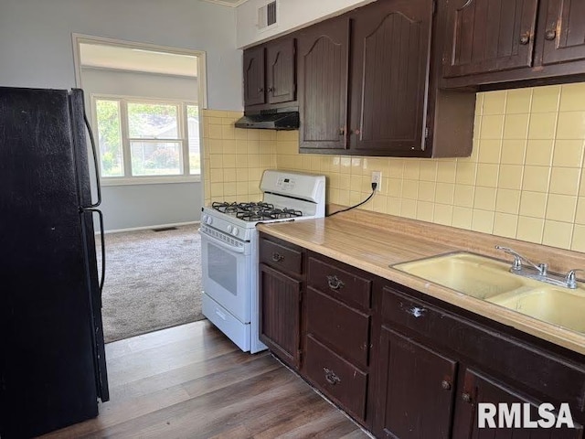 831 W Bartlett Ct, Peoria, IL 61604 - kitchen featuring freestanding refrigerator, white gas range oven, under cabinet range hood, dark brown cabinets, and light countertops