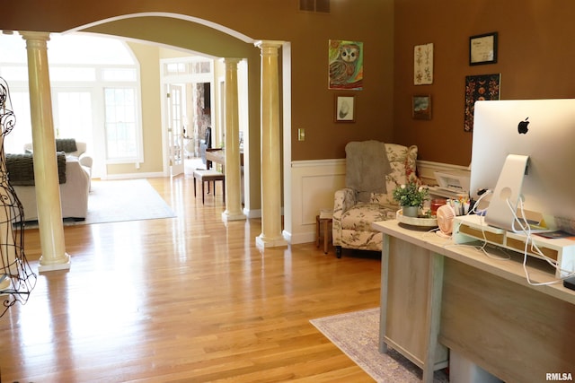 1112 W Cedar Hills Dr, Dunlap, IL 61525 - living room featuring decorative columns, arched walkways, a wainscoted wall, and light wood-style flooring