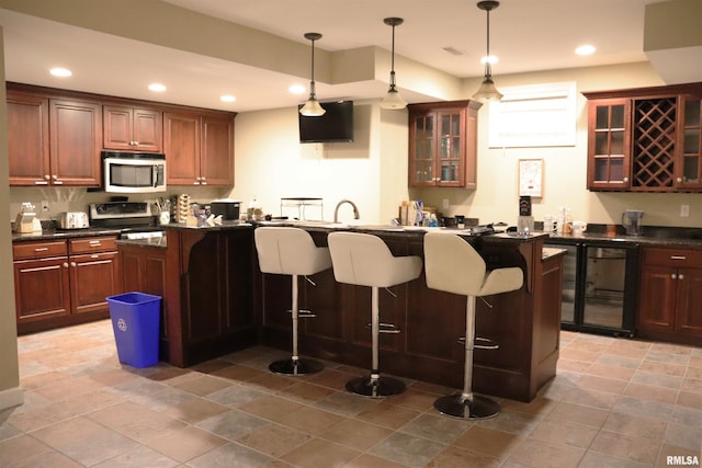1112 W Cedar Hills Dr, Dunlap, IL 61525 - kitchen with appliances with stainless steel finishes, dark countertops, a kitchen bar, recessed lighting, and decorative light fixtures