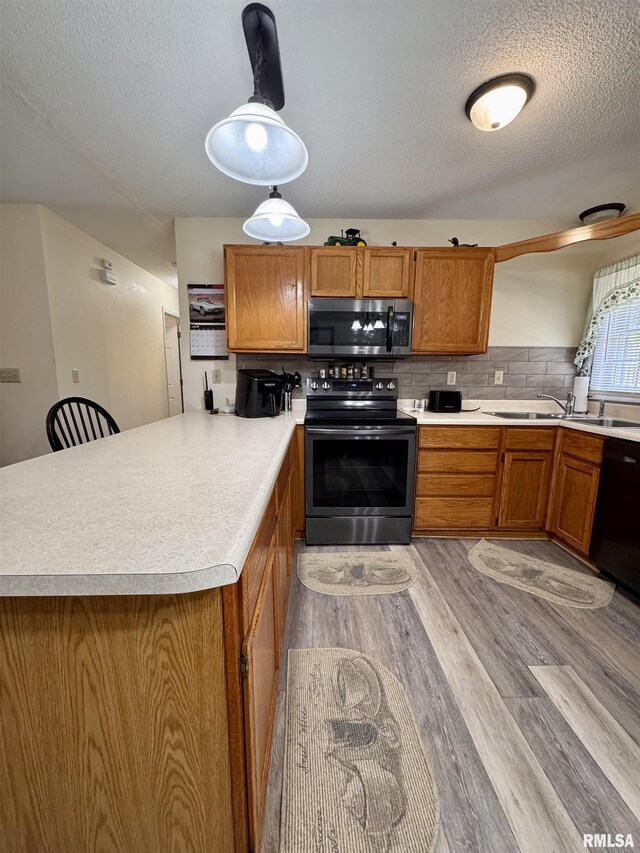 1612 Joyce Ln, Macomb, IL 61455 - kitchen featuring black appliances, a peninsula, brown cabinetry, light countertops, and a textured ceiling