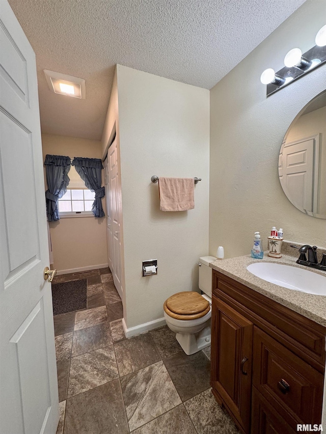 1612 Joyce Ln, Macomb, IL 61455 - bathroom with vanity, toilet, baseboards, a textured ceiling, and stone finish floors