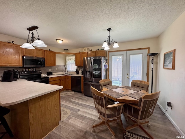1612 Joyce Ln, Macomb, IL 61455 - kitchen with black appliances, a peninsula, decorative backsplash, french doors, and a textured ceiling