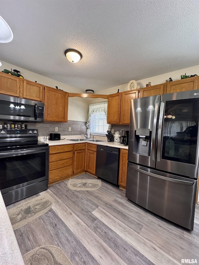 1612 Joyce Ln, Macomb, IL 61455 - kitchen with stainless steel appliances, light countertops, a sink, brown cabinetry, and a textured ceiling