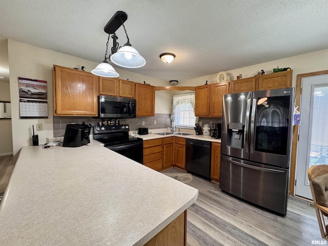 1612 Joyce Ln, Macomb, IL 61455 - kitchen featuring black appliances, a textured ceiling, light wood-type flooring, brown cabinets, and light countertops