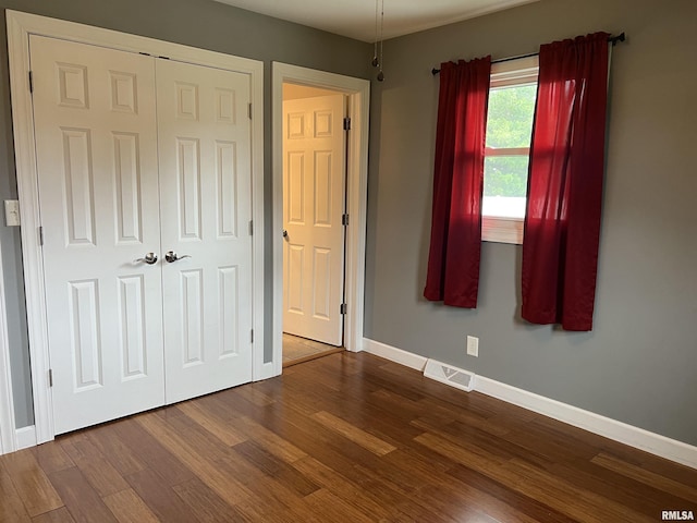 1302 Maple Ave, Macomb, IL 61455 - unfurnished bedroom with dark wood-type flooring, baseboards, and a closet