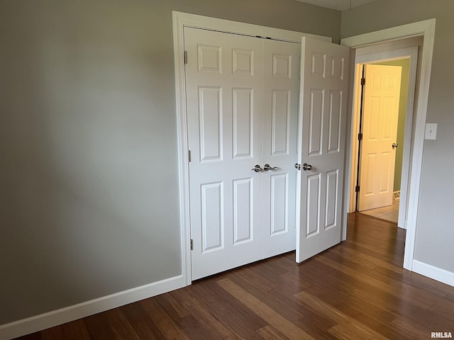 1302 Maple Ave, Macomb, IL 61455 - unfurnished bedroom featuring baseboards, dark wood-style floors, and a closet