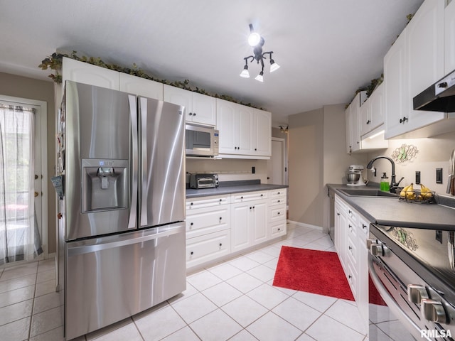2010 E Paris Ave, Peoria, IL 61614 - kitchen featuring stainless steel appliances, light tile patterned floors, white cabinetry, dark countertops, and wall chimney range hood