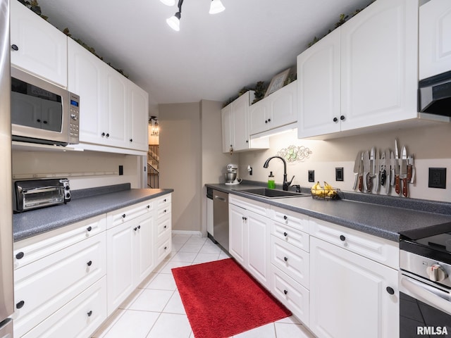 2010 E Paris Ave, Peoria, IL 61614 - kitchen featuring stainless steel appliances, dark countertops, light tile patterned floors, and white cabinets