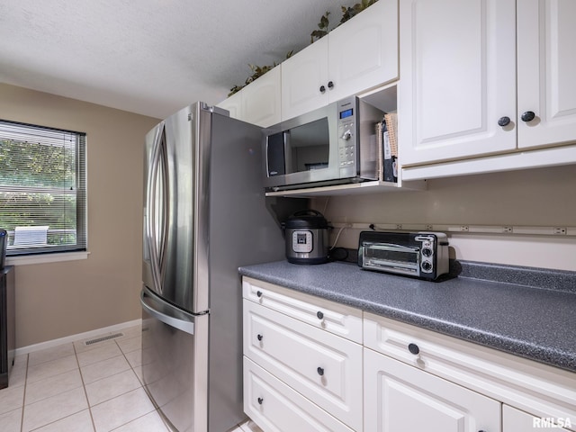 2010 E Paris Ave, Peoria, IL 61614 - kitchen featuring appliances with stainless steel finishes, dark countertops, light tile patterned flooring, and white cabinets