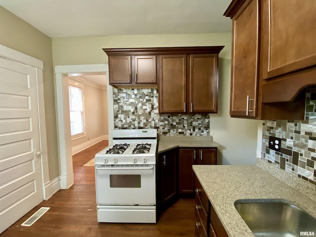 1502 W Columbia Ter, Peoria, IL 61606 - kitchen featuring gas range gas stove, dark wood finished floors, decorative backsplash, light stone counters, and baseboards