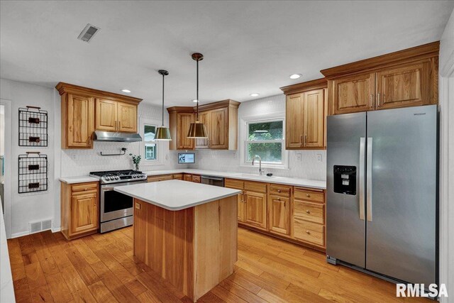 486 E High Point Dr, Peoria, IL 61614 - kitchen featuring appliances with stainless steel finishes, a sink, under cabinet range hood, decorative backsplash, and brown cabinetry