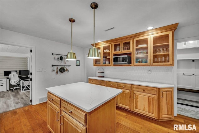 486 E High Point Dr, Peoria, IL 61614 - kitchen featuring stainless steel microwave, decorative backsplash, light wood finished floors, hanging light fixtures, and a kitchen island