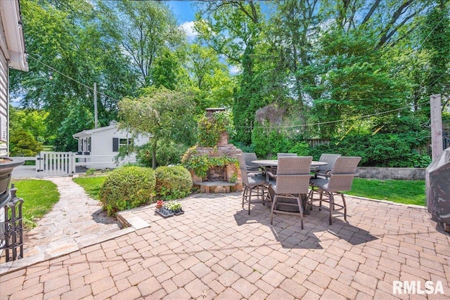 486 E High Point Dr, Peoria, IL 61614 - view of patio featuring an outdoor fireplace, outdoor dining space, a gate, and view of scattered trees