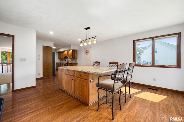 905 Highland Ct, Germantown Hills, IL 61548 - kitchen featuring a breakfast bar, brown cabinets, baseboards, wood finished floors, and recessed lighting