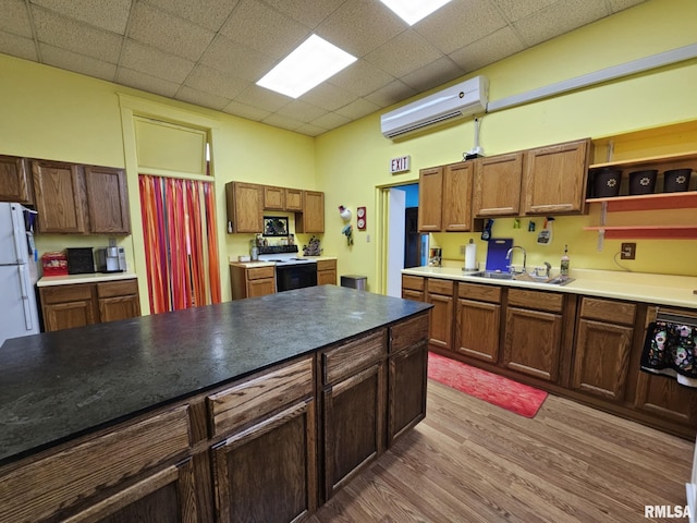 113 N Kickapoo St, Lincoln, IL 62656 - kitchen featuring electric range, a wall unit AC, a sink, wood finished floors, and a paneled ceiling