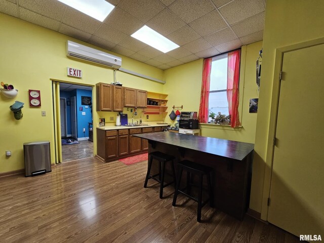 113 N Kickapoo St, Lincoln, IL 62656 - kitchen featuring a wall mounted AC, dark wood finished floors, a paneled ceiling, brown cabinets, and open shelves