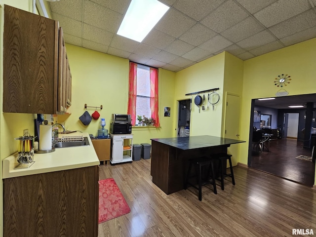 113 N Kickapoo St, Lincoln, IL 62656 - kitchen with a sink, wood finished floors, a kitchen bar, a drop ceiling, and baseboards
