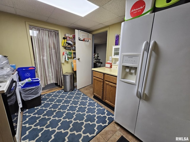 113 N Kickapoo St, Lincoln, IL 62656 - kitchen with white refrigerator with ice dispenser, a drop ceiling, brown cabinets, light countertops, and stainless steel range