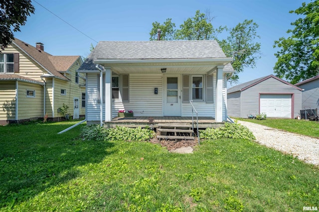 116 S 8th Ave, Canton, IL 61520 - bungalow-style home with covered porch, a detached garage, driveway, a front lawn, and an outbuilding