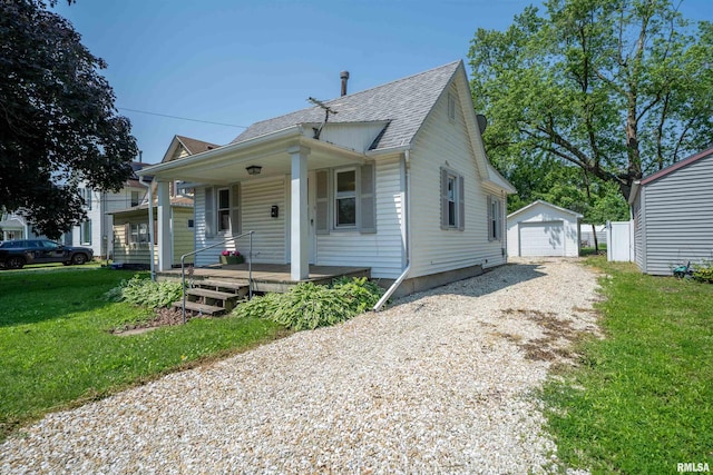 116 S 8th Ave, Canton, IL 61520 - bungalow with dirt driveway, a porch, a shingled roof, an outbuilding, and a front yard