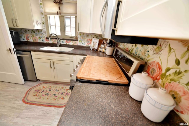 3307 N Biltmore Ave, Peoria, IL 61604 - kitchen with stainless steel appliances, dark countertops, wallpapered walls, and white cabinetry