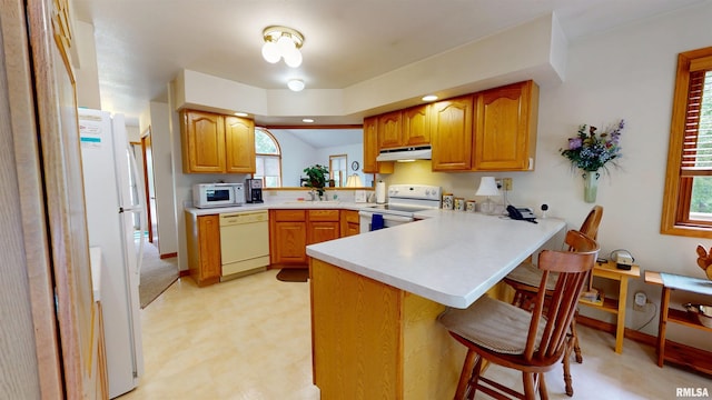 1111 Windy Hill Ct, Varna, IL 61375 - kitchen with white appliances, under cabinet range hood, light flooring, a peninsula, and a breakfast bar