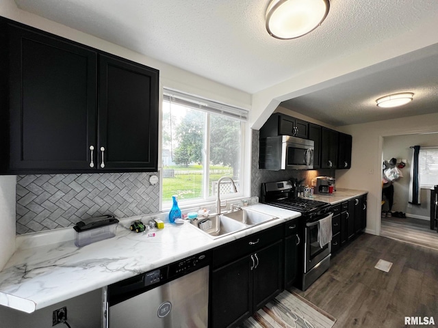 1520 N Finney St, Chillicothe, IL 61523 - kitchen with appliances with stainless steel finishes, dark cabinetry, a sink, backsplash, and wood finished floors