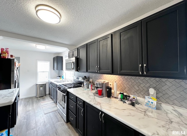 1520 N Finney St, Chillicothe, IL 61523 - kitchen with appliances with stainless steel finishes, dark cabinetry, a sink, tasteful backsplash, and light wood-style flooring