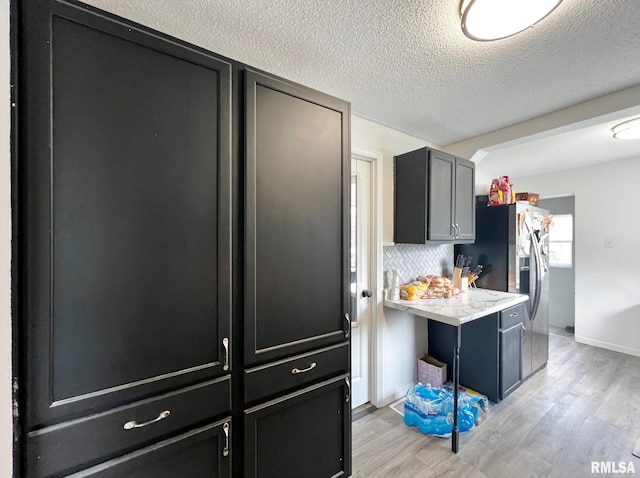 1520 N Finney St, Chillicothe, IL 61523 - kitchen featuring light wood-type flooring, stainless steel fridge, light countertops, a textured ceiling, and dark cabinetry