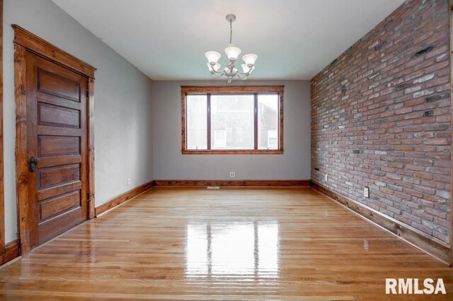 307 N Logan St, Deer Creek, IL 61733 - unfurnished room featuring brick wall, a chandelier, light wood-style floors, and baseboards