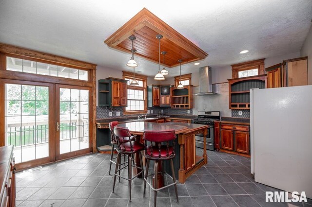 307 N Logan St, Deer Creek, IL 61733 - kitchen featuring open shelves, wall chimney exhaust hood, freestanding refrigerator, gas stove, and recessed lighting