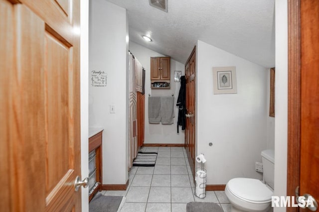 307 N Logan St, Deer Creek, IL 61733 - full bath with lofted ceiling, toilet, tile patterned flooring, a textured ceiling, and baseboards