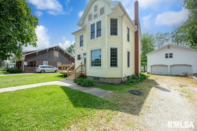 307 N Logan St, Deer Creek, IL 61733 - view of front facade featuring a chimney, a garage, a front lawn, and an outdoor structure