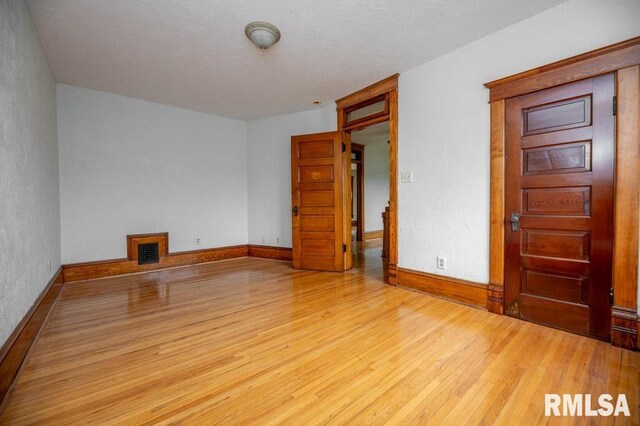307 N Logan St, Deer Creek, IL 61733 - empty room with wood finished floors, baseboards, a textured wall, and a textured ceiling