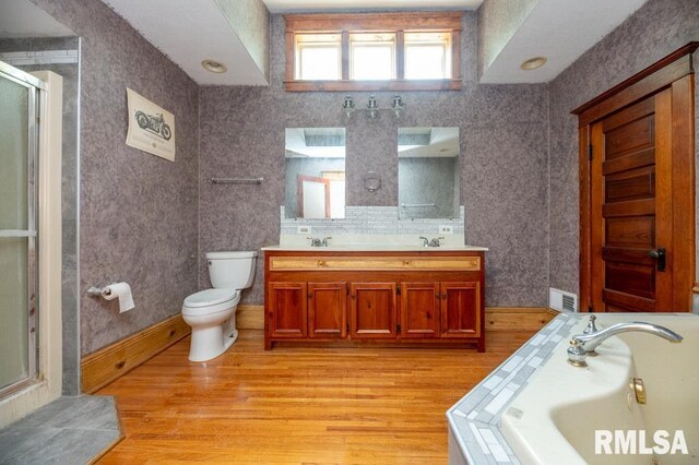 307 N Logan St, Deer Creek, IL 61733 - bathroom with toilet, a shower stall, double vanity, wood finished floors, and a garden tub