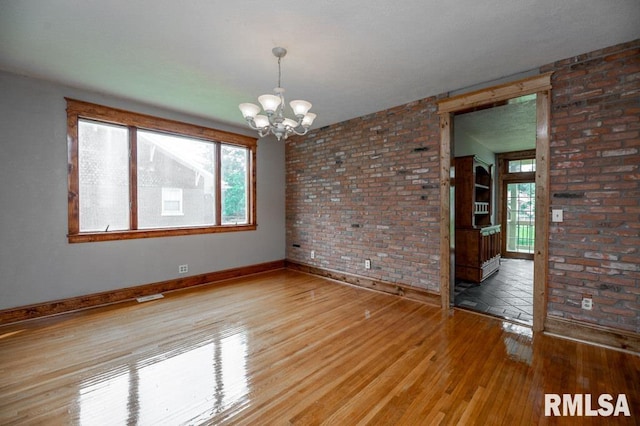 307 N Logan St, Deer Creek, IL 61733 - spare room featuring a chandelier, hardwood / wood-style floors, baseboards, and brick wall