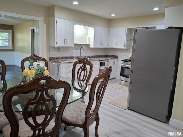 2604 W Kansas St, Peoria, IL 61604 - kitchen with stainless steel appliances, backsplash, white cabinets, light wood-style flooring, and recessed lighting