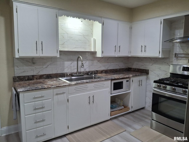 2604 W Kansas St, Peoria, IL 61604 - kitchen featuring stainless steel gas stove, white microwave, backsplash, and white cabinets