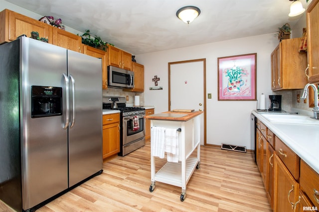 100 Oakridge Ct, Dahinda, IL 61428 - kitchen with appliances with stainless steel finishes, light countertops, brown cabinets, tasteful backsplash, and light wood-type flooring