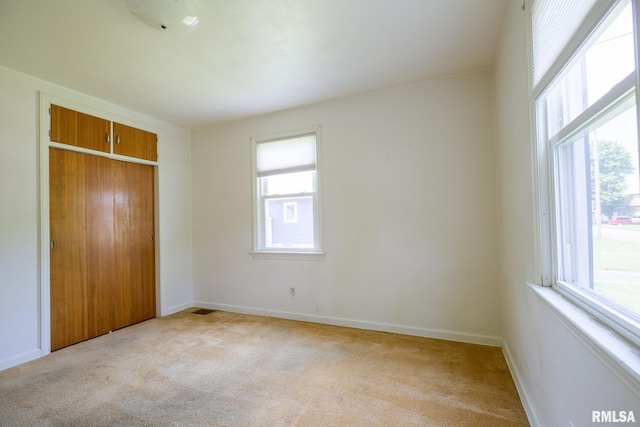 1030 E Euclid Ave, Peoria Heights, IL 61616 - unfurnished bedroom featuring multiple windows, light carpet, and a closet