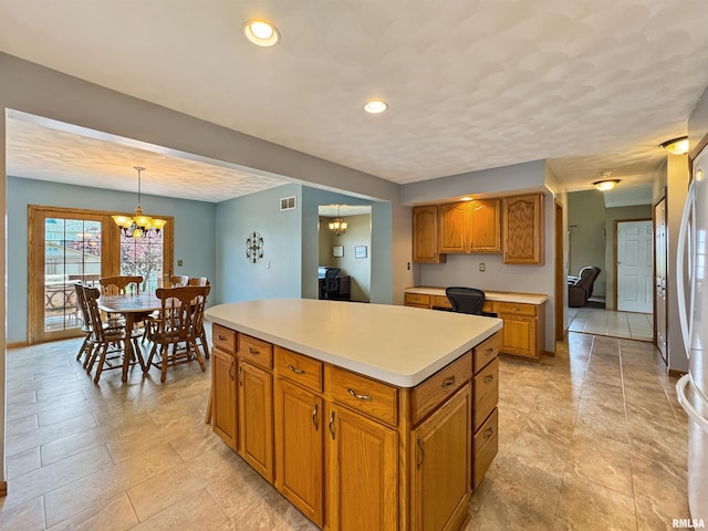 125 Prairieview Dr, East Peoria, IL 61611 - kitchen featuring a chandelier, light countertops, brown cabinets, a center island, and hanging light fixtures