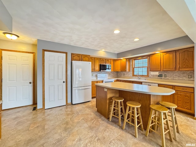 125 Prairieview Dr, East Peoria, IL 61611 - kitchen featuring white appliances, brown cabinetry, light countertops, tasteful backsplash, and recessed lighting