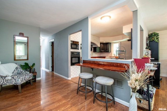 324 Pinecrest Dr, Germantown Hills, IL 61548 - kitchen featuring black appliances, wood finished floors, a breakfast bar area, and a peninsula