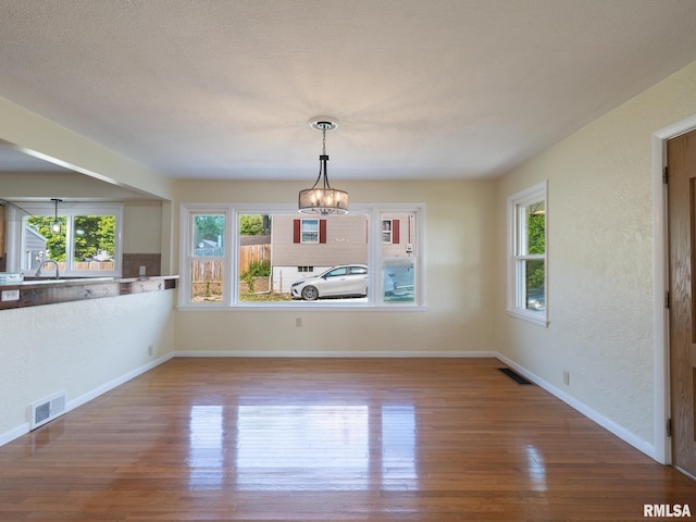 621 E Sciota Ave, Peoria Heights, IL 61616 - unfurnished dining area featuring a chandelier, wood finished floors, and a textured wall
