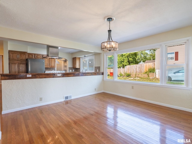 621 E Sciota Ave, Peoria Heights, IL 61616 - kitchen with freestanding refrigerator, island exhaust hood, brown cabinets, light wood-style flooring, and dark countertops
