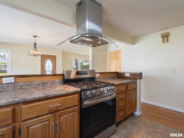 621 E Sciota Ave, Peoria Heights, IL 61616 - kitchen with stainless steel gas stove, island exhaust hood, brown cabinets, dark tile patterned flooring, and a chandelier