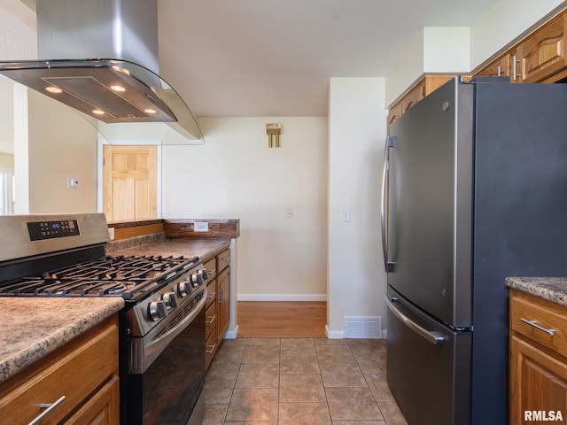 621 E Sciota Ave, Peoria Heights, IL 61616 - kitchen featuring stainless steel appliances, wall chimney range hood, brown cabinets, and tile patterned floors